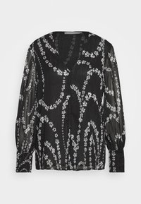 Blouse longue noire transparente à manches longues avec motifs floraux blancs en forme de vigne et poignets boutonnés, avec un col en V et un tissu léger.