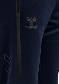 Navy sportbroek met een slim fit, een gladde stof, een zak met rits en reflecterende zwarte accenten met het "Hummel" logo.