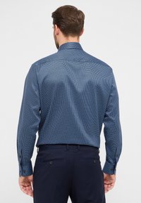 Camicia blu navy a motivo con maniche lunghe, polsini con bottone e colletto strutturato, realizzata in tessuto liscio, caratterizzata da un sottile design geometrico.