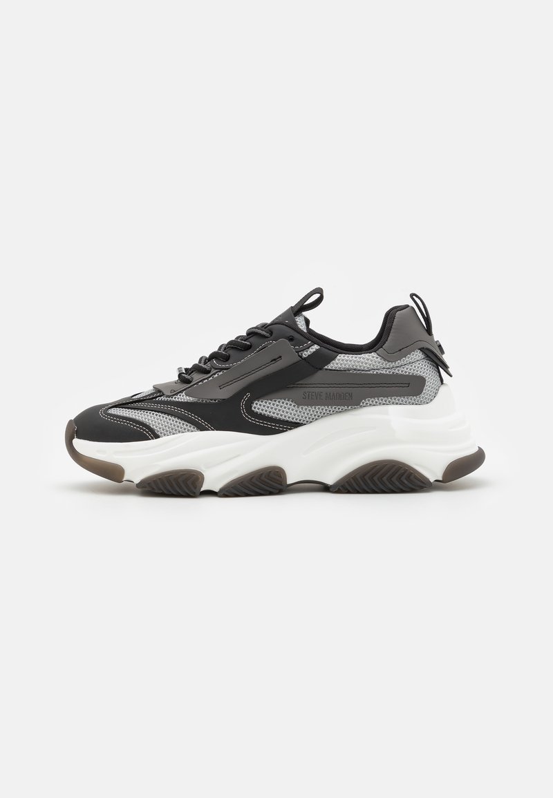 Chunky sneaker in black, gray, and white. Features mesh and synthetic upper, lace-up design, and a thick white sole with textured brown outsole.