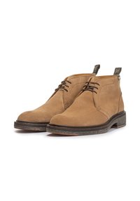 Botas de ante marrón con diseño de cordones, punta redonda y una suela de goma oscura contrastante. Incluyen una pestaña trasera para un fácil calzado.