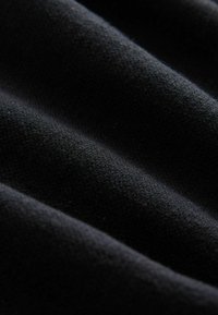Crni materijal s mekanom teksturom, koji sadrži suptilne valovite uzorke i gustu tkanje, stvarajući bogatu vizualnu dubinu i ravnomjernu raspodjelu boje.