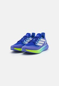 Chaussures de sport bleues avec un dessus en mesh respirant, des rayures blanches et une semelle en caoutchouc texturé avec un accent vert. Design léger.