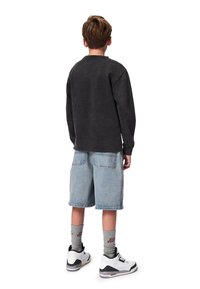 Mustat pitkähihaset collegepaidat, vaaleansiniset farkkushortsit, harmaat sukat ja valkoiset lenkkarit. Näkymä takaa. Rento istuvuus ja vapaa tyyli.