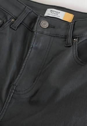 Sorte bootcut jeans med mellem-høj talje, der har syede sømme, metalknaplukning og et mærke, der viser størrelse og materialedetaljer.