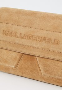 Clutch in suede color tan con superficie testurizzata, caratterizzata da branding embossato "Karl Lagerfeld" e dettagli di cuciture geometriche.