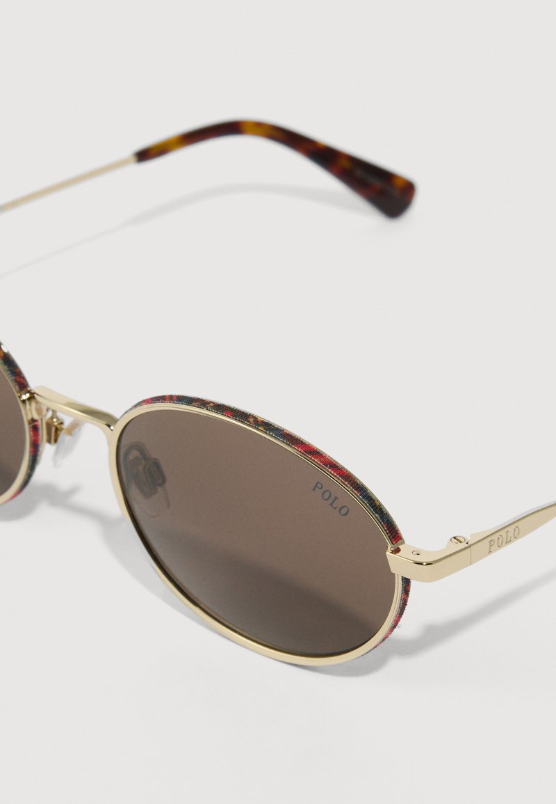 Gold-framed sunglasses with brown lenses, featuring a textured plaid pattern on the rims and tortoiseshell temple accents. "POLO" logo present.