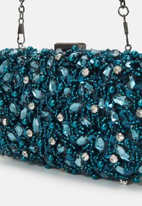 Clutch-väska med mörk teal-pärlor, paljetter och kristallsmycken, med en metalldetalj som axelrem och rektangulär lås.