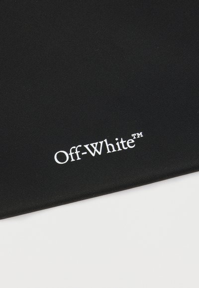 Μαύρο ύφασμα με λευκό λογότυπο "Off-White™" τυπωμένο κοντά στην κάτω άκρη, τοποθετημένο σε λευκό φόντο.