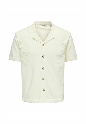Chemise crème à manches courtes avec col ouvert, cinq boutons marron et motifs floraux délicats en maille sur les côtés avant.