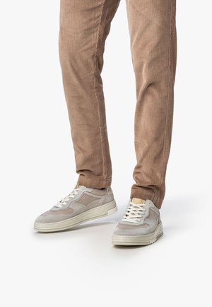 Sneakers in lichtgrijs suède met beige accenten en witte veters. Rond toe, met een gestructureerd ontwerp en een stevige witte zool. Corduroy broek in tan.