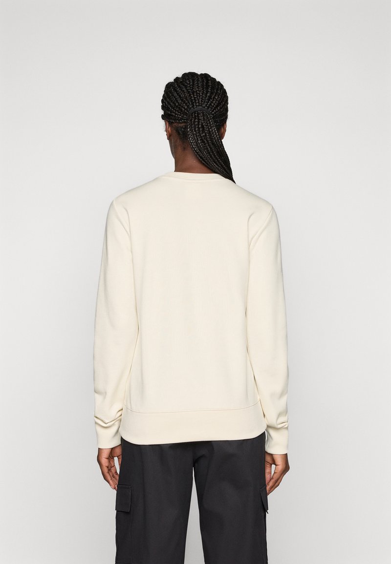 Helles beiges Sweatshirt, Rundhalsausschnitt, lange Ärmel, strukturierter Stoff, gerippte Bündchen und Saum, einfaches Design, getragen mit dunklen Cargo-Hosen.