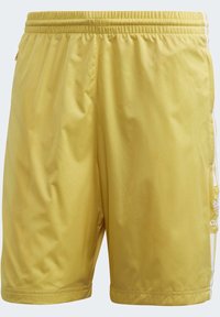 Gula sportshorts av lättviktsmaterial med elastisk midja, har vita sidostråk och en lös passform.