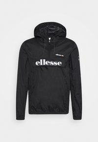 Schwarze ellesse Windbreaker-Jacke mit Frontreißverschluss, Kapuze und großem weißem ellesse-Logo über der Brust sowie kleinem Logo auf der oberen rechten Seite.