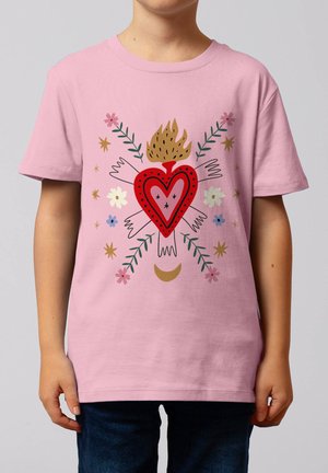 Enfant portant un t-shirt rose avec un cœur rouge flamboyant entouré de mains blanches, de fleurs, d'étoiles, de branches vertes et d'un croissant de lune doré.