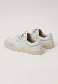 Weißleder-Sneaker mit grauen Wildlederakzenten, runder Zehenpartie, flacher cremefarbener Sohle und Schnürdesign. Verfügt über Perforationen an den Seiten.