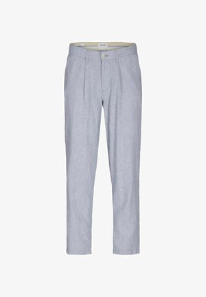 Wit linnen shirt met korte mouwen en knopen aan de voorkant, gecombineerd met lichtblauwe gestreepte broek. Witte sneakers maken de outfit compleet.