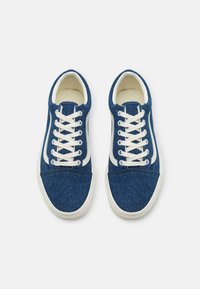 Blue denim sneakers with white leather accents, featuring a low-top design, round toe, and six pairs of white laces threaded through eyelets.