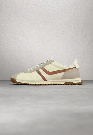 Baskets beige et marron à lacets avec semelle en caoutchouc et logo BOSS sur le côté, présentées sur une surface grise avec un fond neutre.