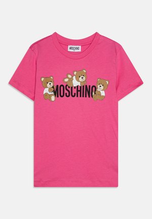 Roza bombažna majica s kratkimi rokavi, ki prikazuje tri risane medvede in besedilo "MOSCHINO" v črni barvi. Ima okroglo ovratnik.