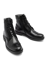 Czarne skórzane botki za kostkę z sznurówkami z przodu, bocznym zamkiem błyskawicznym i filcowymi detalami. Gładka tekstura, okrągły czubek i płaska podeszwa.