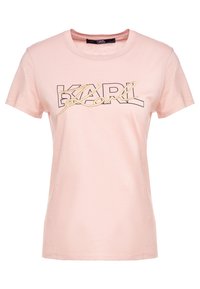 Vaaleanpunainen lyhythihainen puuvillainen t-paita, jossa on musta ja kulta kirjailtu graafinen logo etupuolella. Klassinen pyöreä pääntie.