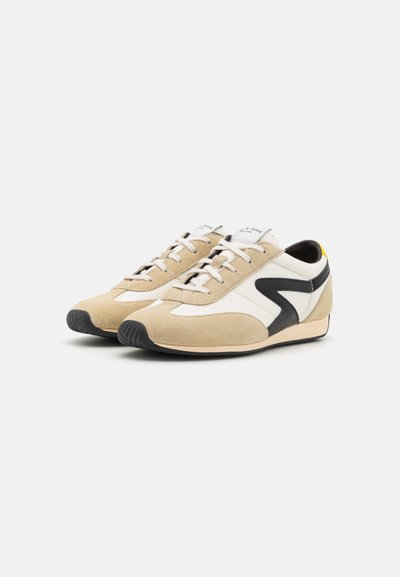 Beige suede and white leather sneakers with black accents, lace-up design, low profile, and textured rubber outsole.