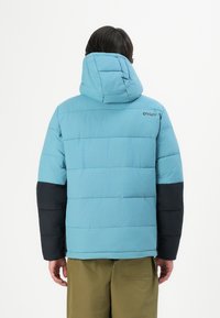 Giacca puffer blu con cappuccio, con maniche nere e trapuntatura orizzontale. Il logo del marchio è posizionato in modo discreto sulla spalla posteriore.