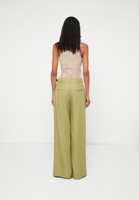 Μπεζ υφασμάτινο τοπ και παντελόνι σε ελιά πράσινο με φαρδιές �φόρμες και πλαϊνές τσέπες. Το παντελόνι διαθέτει πίσω ελαστική μέση με δύο διακοσμητικές ραφές.