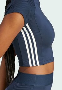 Navy blå cropped sports top lavet af struktureret stof, med hvide striber på skuldrene og subtil branding på taljen.