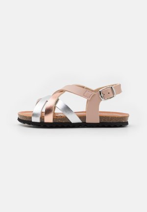 Strappy sandal with pink, rose gold, and silver metallic accents. Features a buckle, cork sole, and textured black bottom for traction.