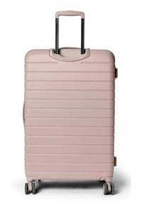 Valise à coque rigide de couleur rose pâle, présentant une texture nervurée, une poignée rétractable et des roues pivotantes pour faciliter la mobilité.