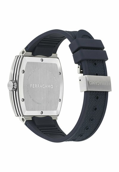 Négyzet alakú rozsdamentes acél karóra kefélt ezüst hátlappal, sötétkék gumiszíjjal, amely geometrikus mintázatú, ezüst kiegészítőkkel.