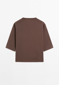 Brown oversized short-sleeve shirt with a crew neck, displayed flat against a white background, showing the back side.