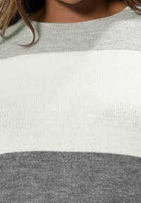 Sweter dzianinowy w poziome paski w jasnoszarym, białym i ciemnoszarym kolorze. Miękka faktura i ściągacz przy dekolcie.