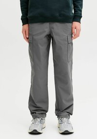 Sive cargo hlače ravnog kroja, s bočnim džepovima i izrađene od lagane tkanine, u kombinaciji sa sivim sportskim cipelama.