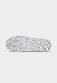 Λευκή σόλα παπουτσιού Nike με σχέδιο λωρίδας ψαροκόκαλου και λογότυπο Nike ανάγλυφο κοντά στην καμάρα σε απλό ανοιχτό γκρι φόντο.