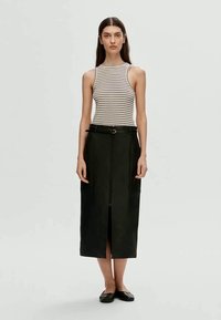 Saias midi pretas com fecho na frente e detalhe de cinto, combinadas com uma blusa sem mangas riscada. O modelo está em uma pose neutra e usa sapatilhas pretas.