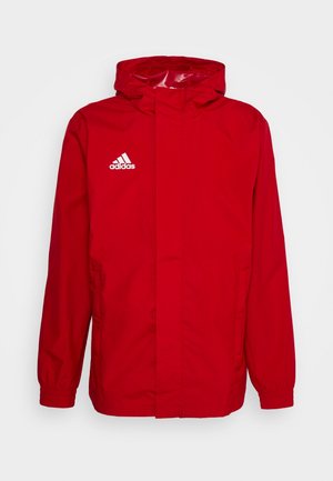 Chaqueta con capucha roja de Adidas con puños elásticos y cremallera frontal oculta, con el logo blanco de Adidas en el pecho.
