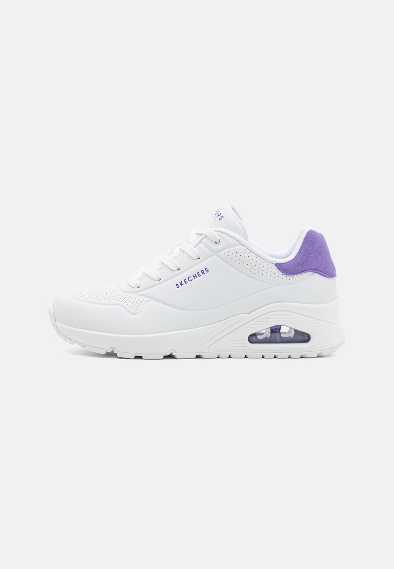 Zapatilla blanca con acentos morados, que presenta una parte superior suave, secciones perforadas y una unidad de aire visible en el talón para amortiguación.