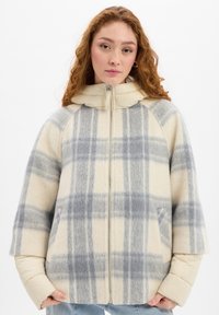 Plaid jacket in cream and gray tones. Made of wool with a soft texture, featuring a zip closure, hood, and two front pockets.