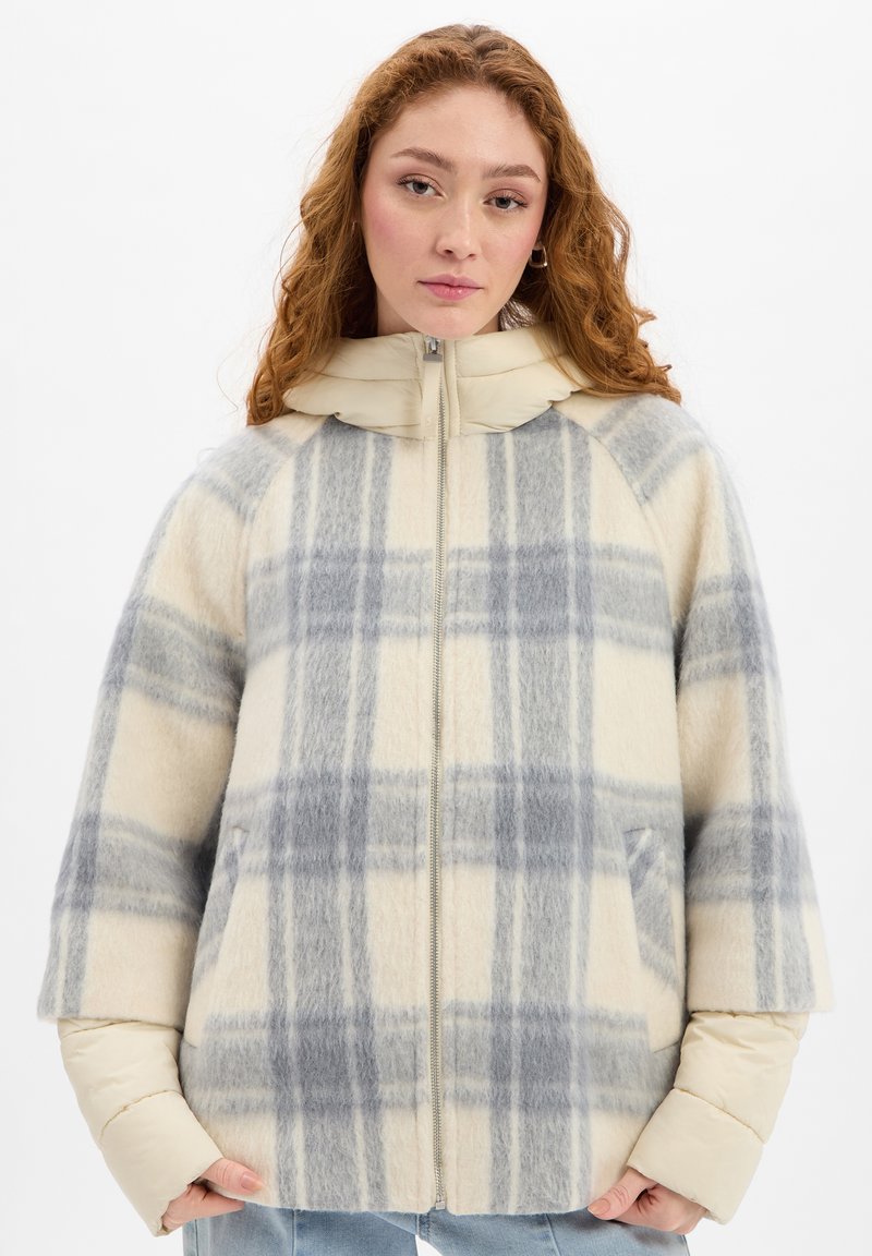 Plaid jacket in cream and gray tones. Made of wool with a soft texture, featuring a zip closure, hood, and two front pockets.