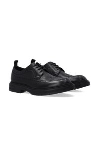 Czarne skórzane buty brogsy z grubą podeszwą, wzorem typu wingtip, perforowanym wykończeniem i sznurowanym zapięciem, przedstawione obok siebie na białym tle.