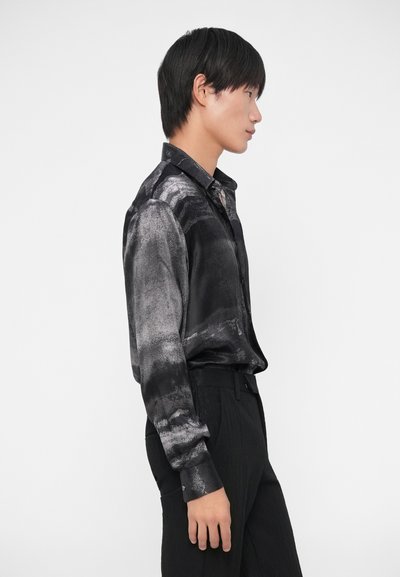 Zwart en grijs button-up shirt met een getextureerd, abstract patroon; lange mouwen en een standaard kraag, gecombineerd met zwarte broek.