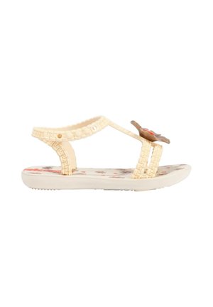 Sandalo per bambino color crema con cinturini intrecciati, plantare stampato con motivi floreali e decorazione a fiore marrone sulla fascia frontale.