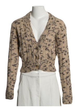 Cárdigan beige corto de punto con patrón moteado oscuro y tres botones marrones, combinado con pantalones blancos de talle alto.