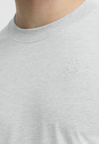 Gray cotton T-shirt featuring a crew neckline and a subtle embossed logo detail on the chest. Soft texture with a plain design.