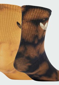 Calze di cotone in arancione bruciato e tie-dye nero. Presentano una texture a coste e un dettaglio del logo bianco a contrasto su ciascuna.