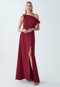 Ühe õlaga burgundia värvi õhtukleit küljetõmblusega. Sile kangas, volditud disain ja delikaatne sõlme detail õlal.