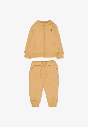 Żółty dres bawełniany, składający się z kurtki zapinanej na zamek z bocznymi kieszeniami oraz dopasowanych spodni dresowych z elastycznym paskiem i bocznymi szwami.